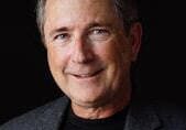 Richard Kahn in a black shirt and grey suit jacket.